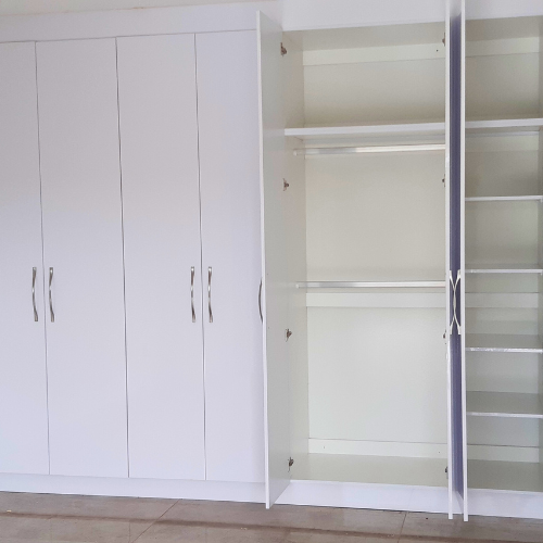 bedroom built-in cupboard. White. Some doors open showing the inside.